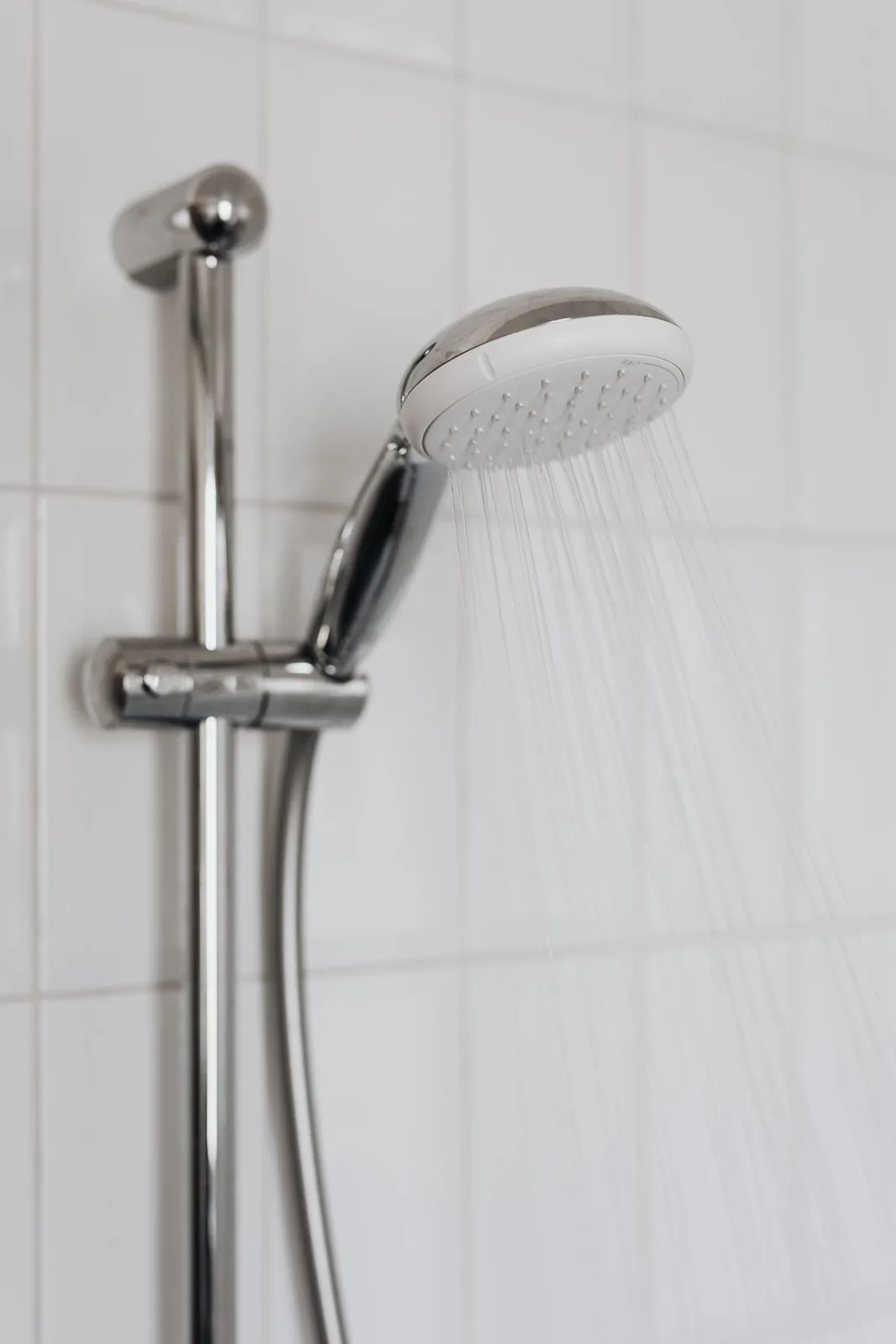Douchette sur barre de fixation dans une salle de bain carrelée